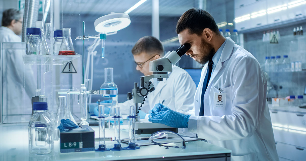 Foto de dos técnicos dentro de un laboratorio investigando componentes biológicos utilizando sus herramientas.